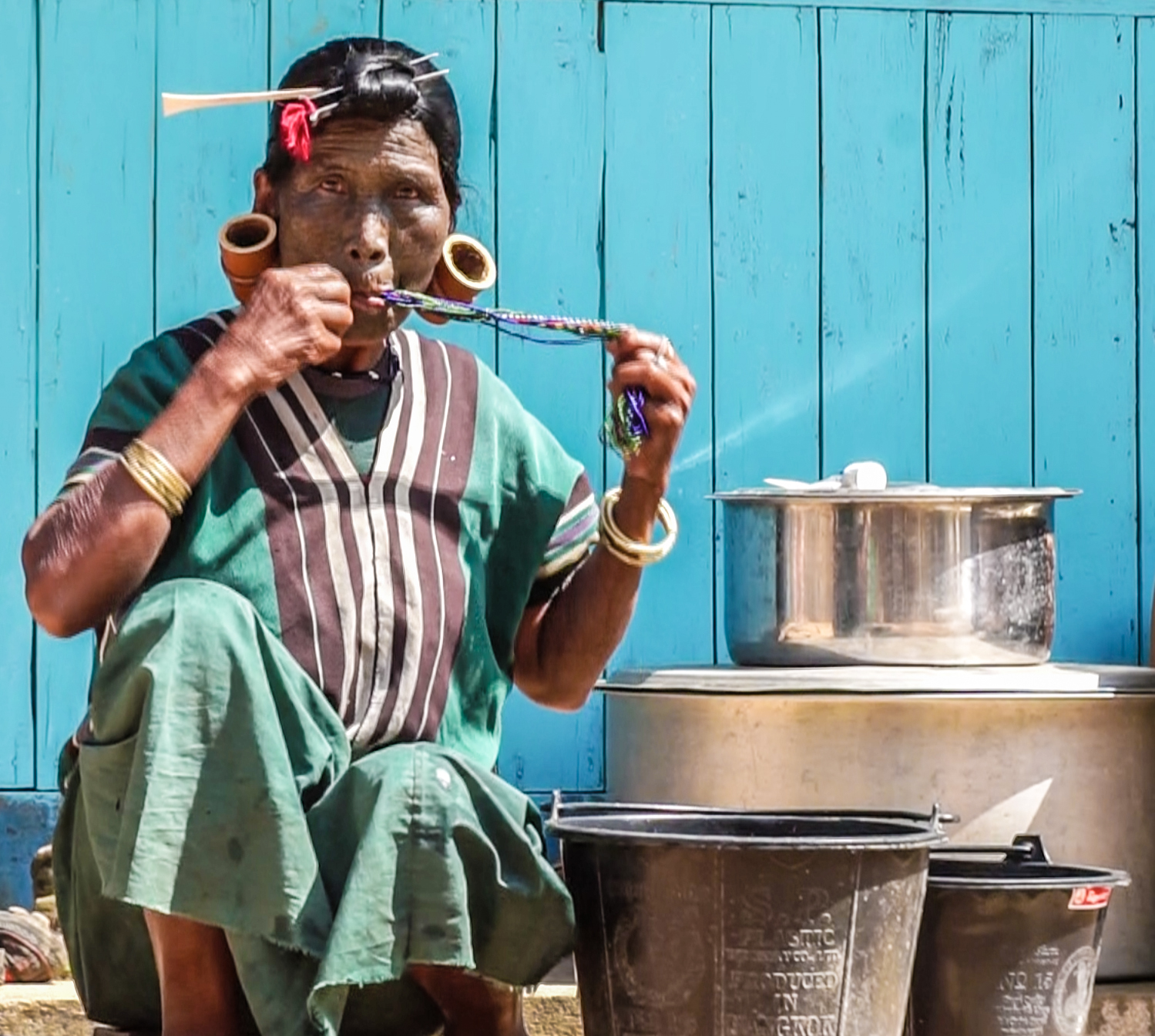Bà Daw Hang Pai (70 tuổi, người Uppriu) đang dùng miệng để vệ sinh bộ trang sức truyền thống của mình ở công đoạn cuối sau khi đã làm sạch.