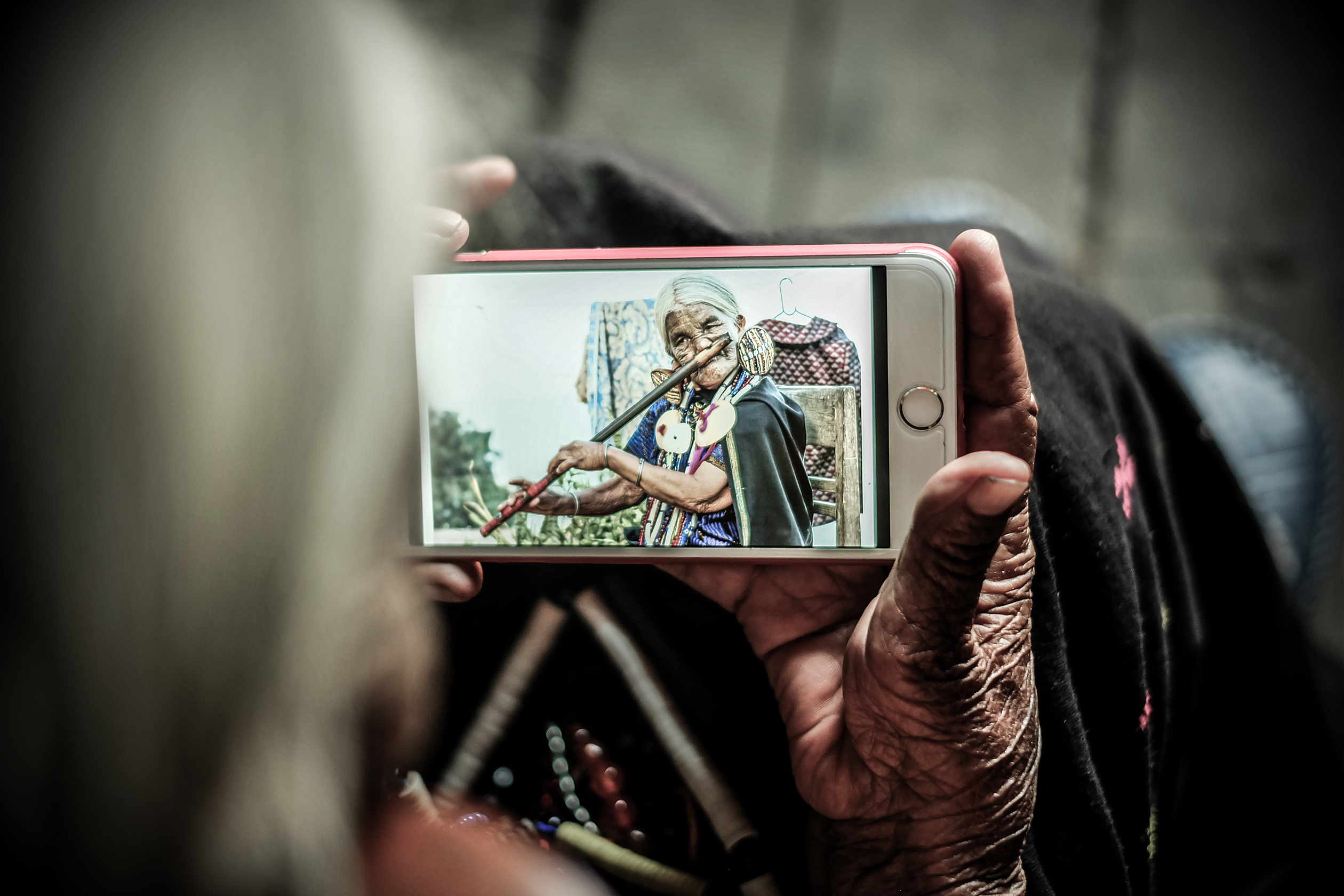 Bà Yaw Shen được một du khách cho xem tấm ảnh nổi tiếng của bà trên thế giới, qua một chiếc điện thoại. 